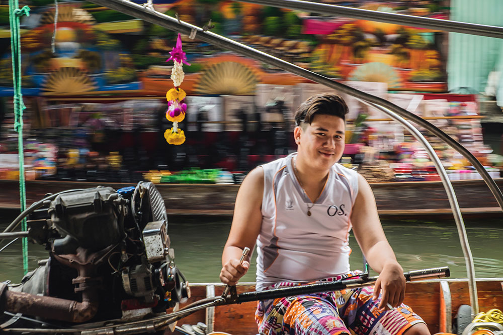 Damnoen Saduak floating market young man smiling Bangkok Thailand